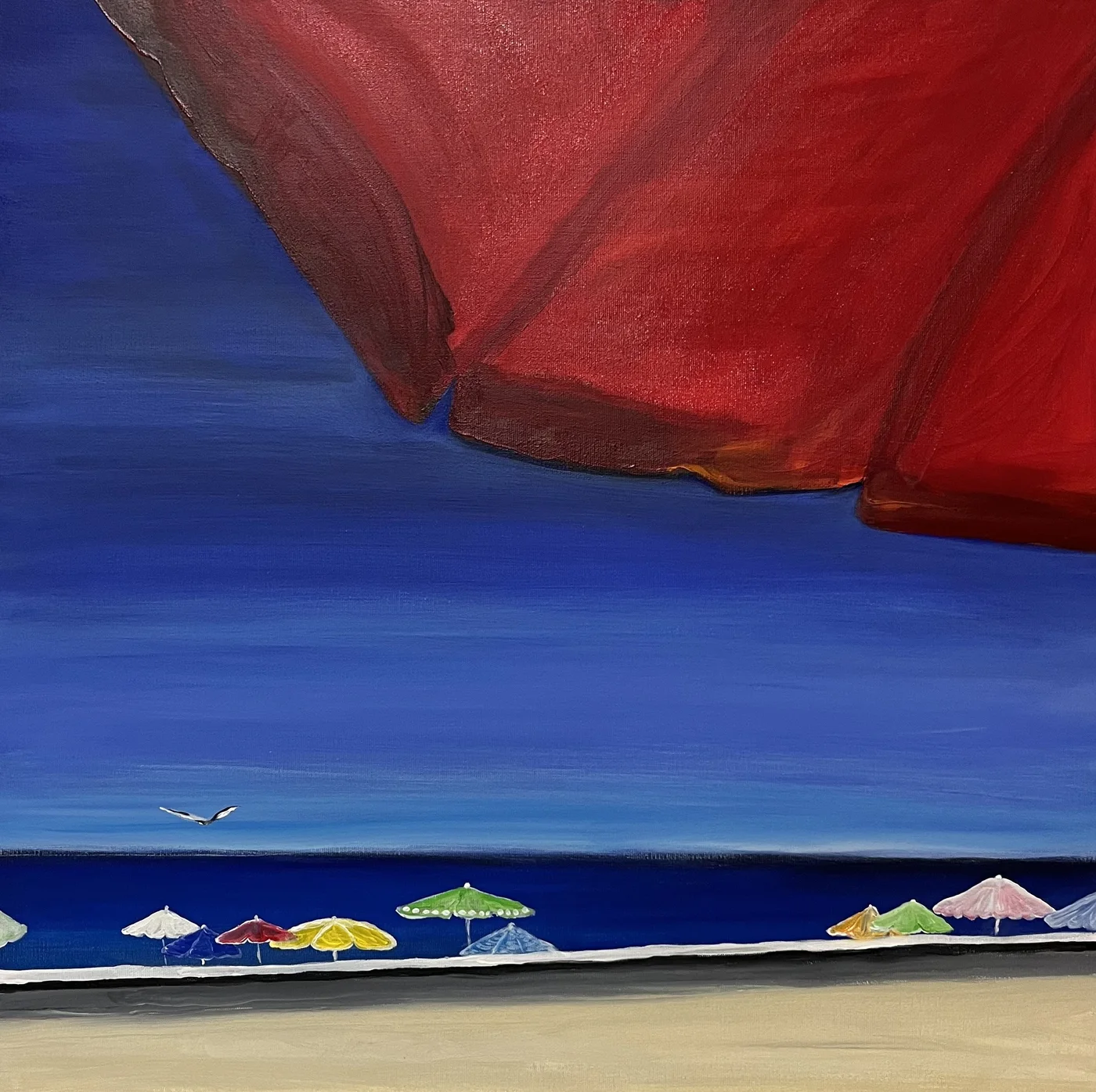 Rotes Segel über blauem Meer und einer Reihe bunter Sonnenschirme